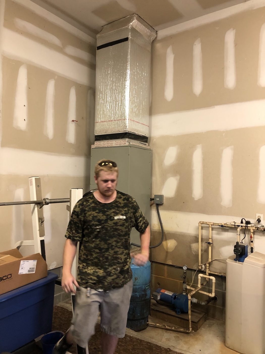 Technician beside a newly installed vertical air handler and duct