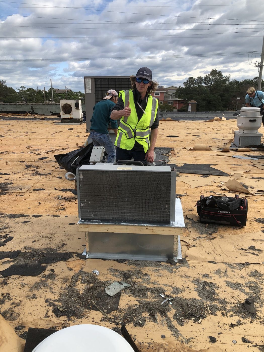 Crew member in safety vest installing a rooftop unit
