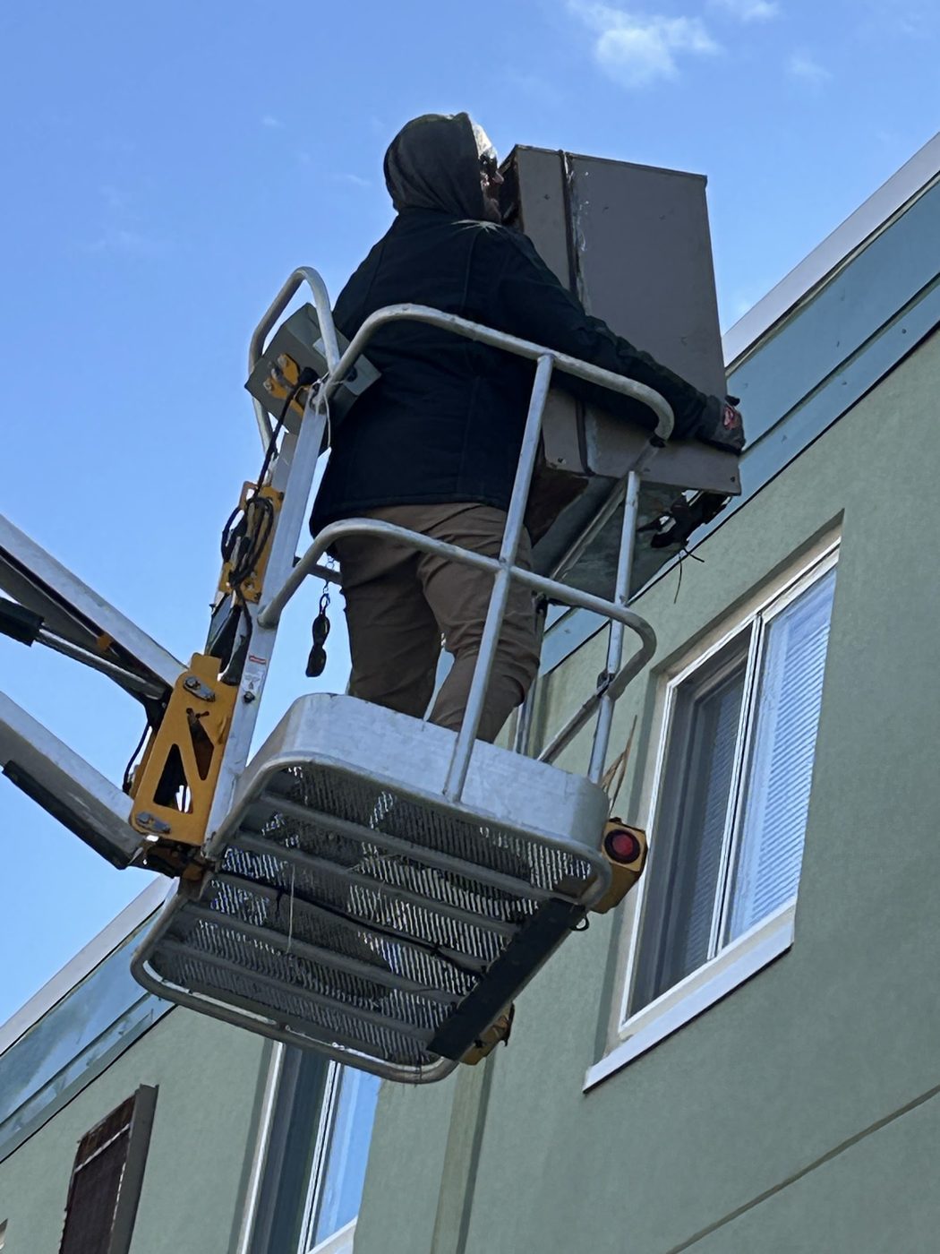 Technician on a boom lift setting equipment on a condo wall
