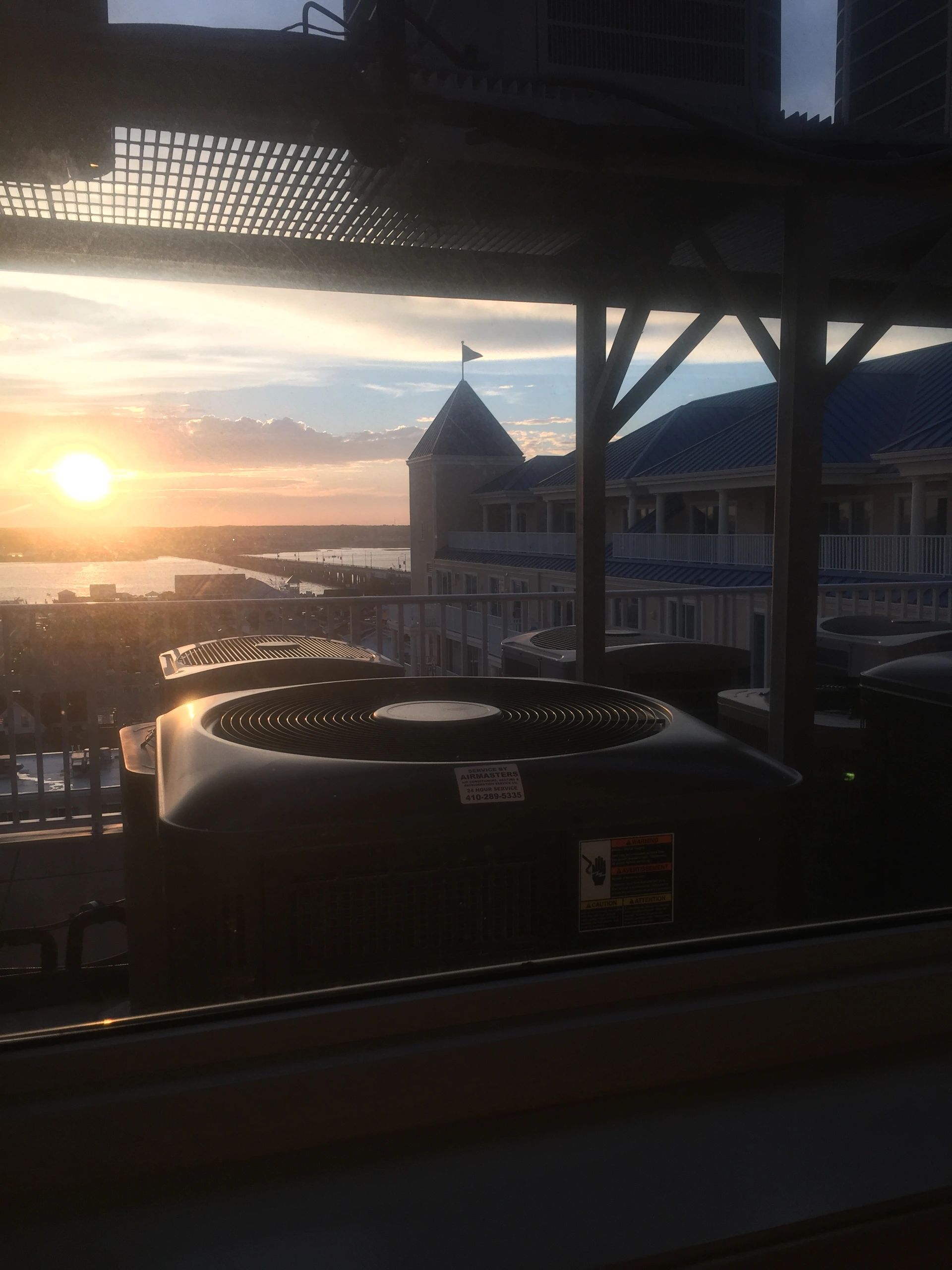 Rows of rooftop heat pumps at a coastal condo building at sunrise