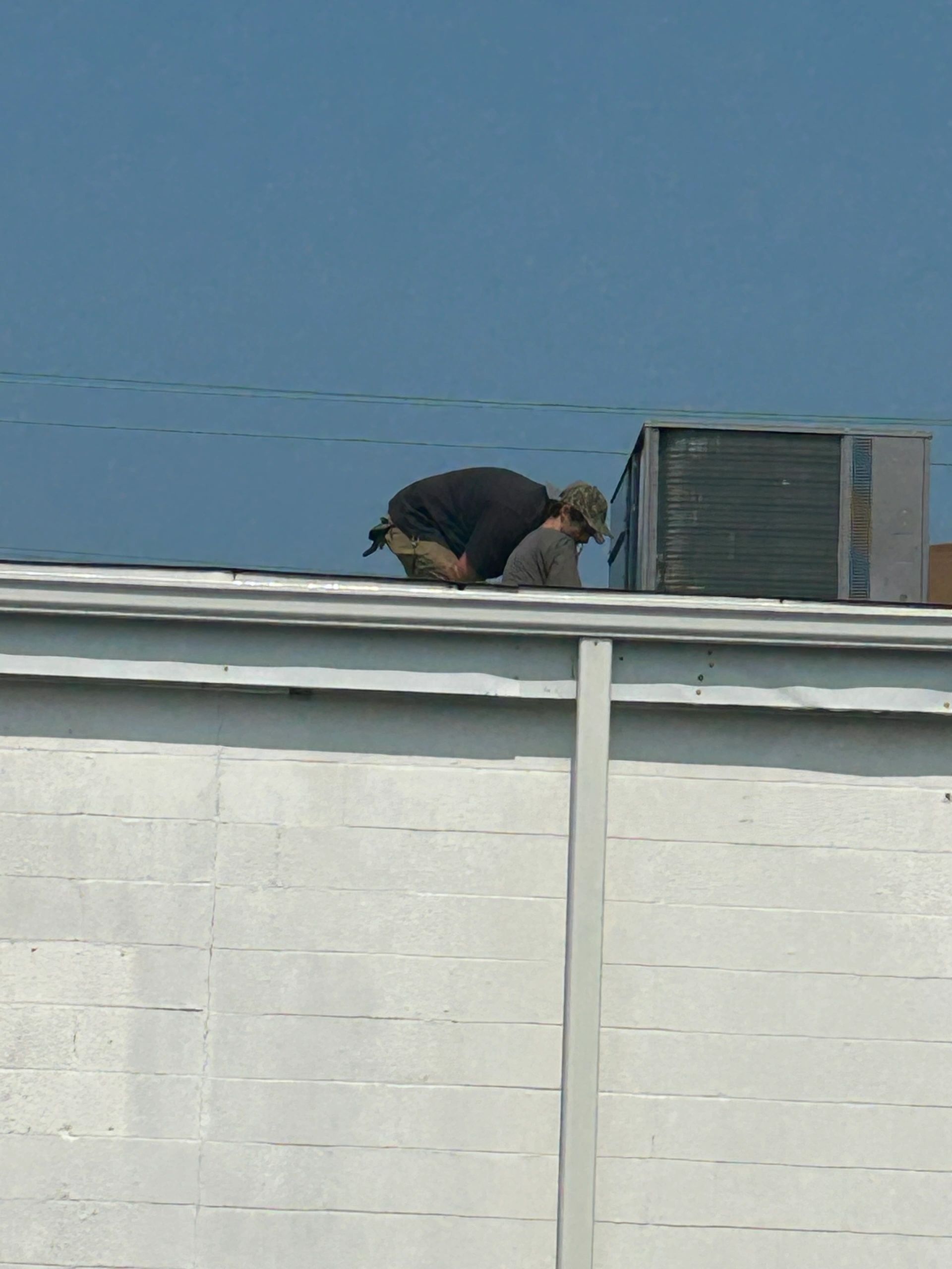 Technician installing a rooftop HVAC unit on a commercial building