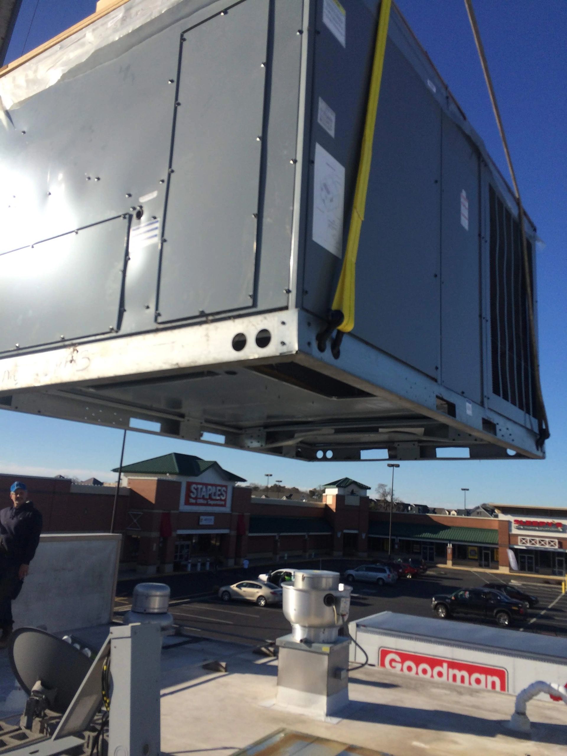 Large commercial rooftop HVAC unit being crane-lifted into place