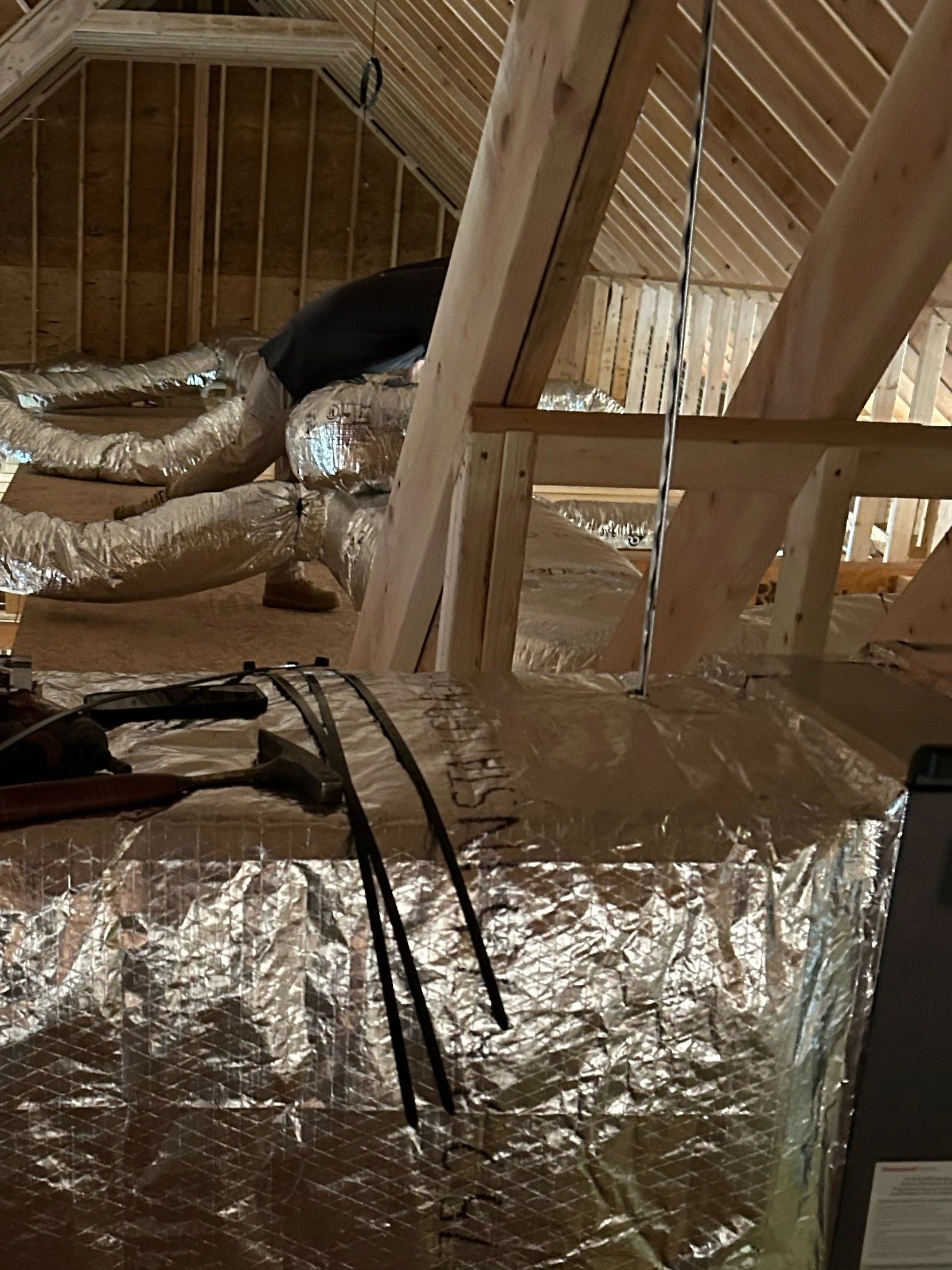New insulated ductwork being installed in an attic during a system replacement