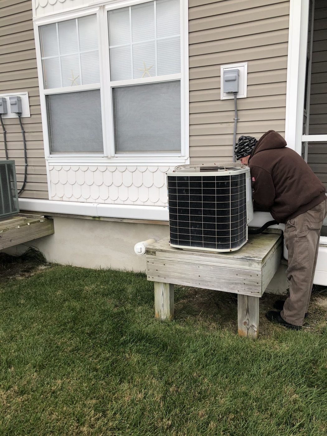 Jim Schiffler crew member servicing an outdoor condenser on a raised platform