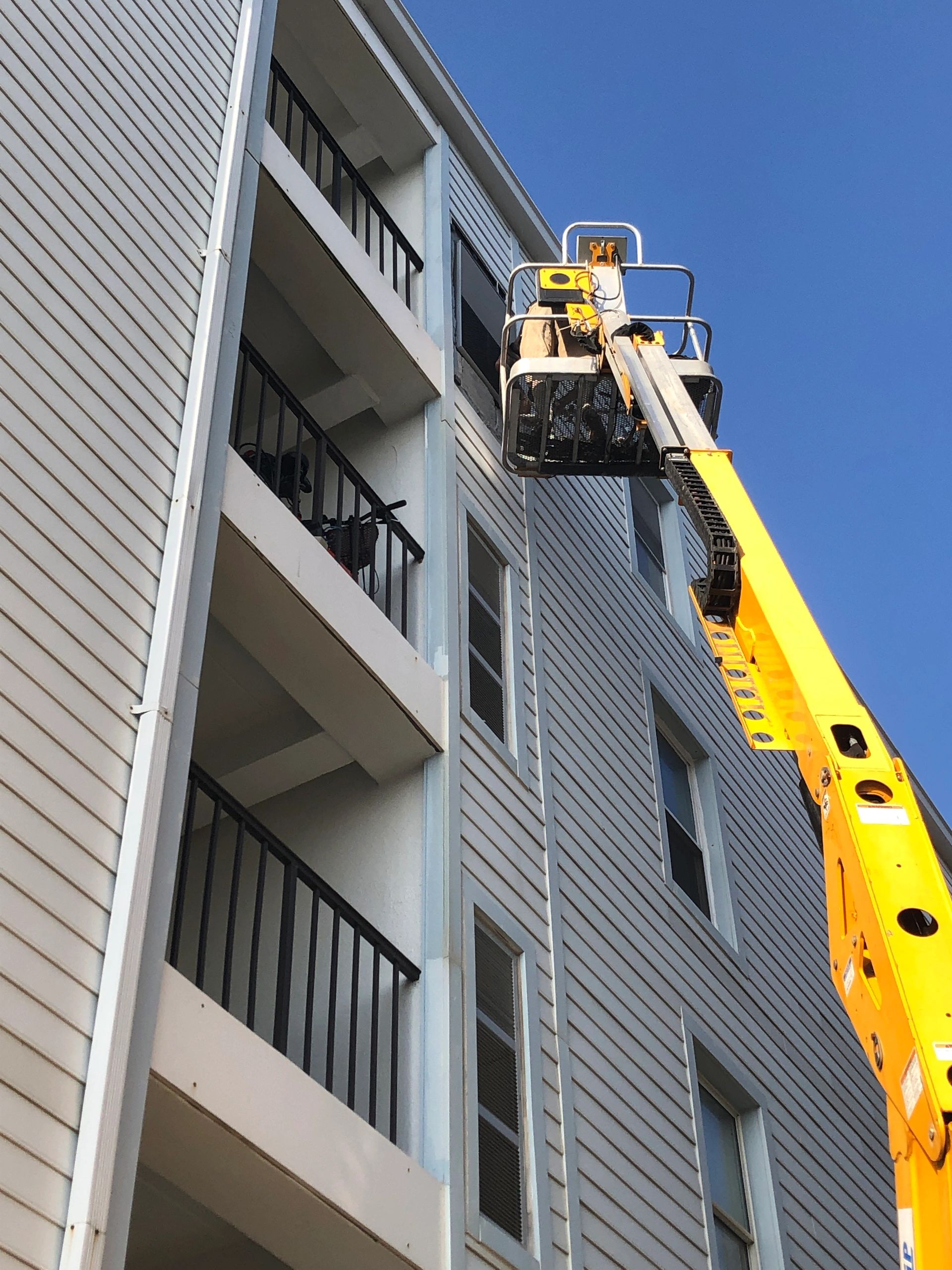 Boom lift reaching upper floors of a condo building for HVAC installation